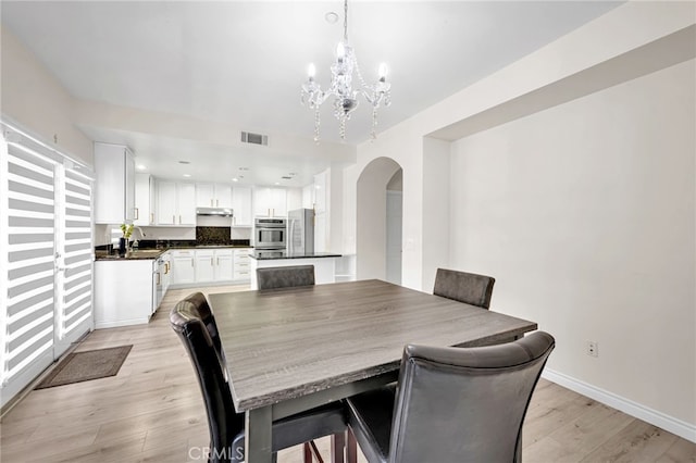 3470 E Temple Way, West Covina, CA 91791 - dining room featuring arched walkways, a chandelier, and light wood finished floors