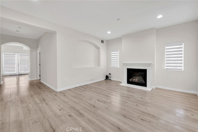 3470 E Temple Way, West Covina, CA 91791 - unfurnished living room featuring arched walkways, a fireplace with flush hearth, light wood-style flooring, plenty of natural light, and recessed lighting