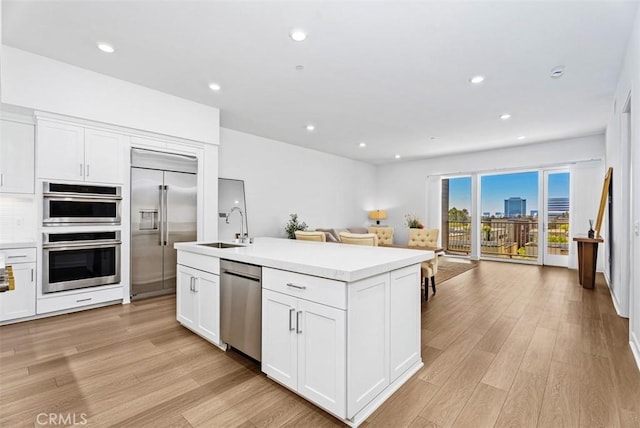 1505 Rivington, Irvine, CA 92612 - kitchen with stainless steel appliances, open floor plan, light wood-style flooring, white cabinets, and recessed lighting
