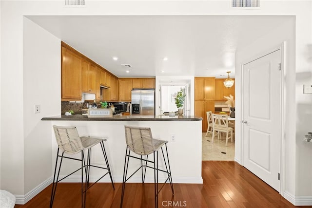 68 E Bay State St Unit 3F, Alhambra, CA 91801 - kitchen featuring stainless steel refrigerator with ice dispenser, a peninsula, dark wood finished floors, a breakfast bar area, and dark countertops