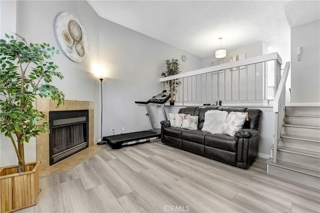 2620 W Grand Ave Unit E, Alhambra, CA 91801 - living room with lofted ceiling, a tiled fireplace, wood finished floors, and stairway