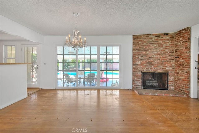 902 W Lucille Ave, West Covina, CA 91790 - unfurnished dining area featuring a textured ceiling, wood finished floors, a chandelier, and a fireplace