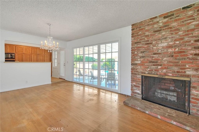 902 W Lucille Ave, West Covina, CA 91790 - unfurnished living room featuring a chandelier, wood finished floors, a textured ceiling, and a fireplace