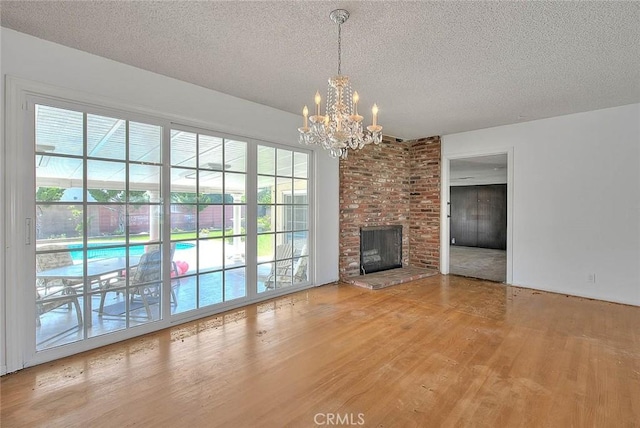 902 W Lucille Ave, West Covina, CA 91790 - unfurnished living room with wood finished floors, a textured ceiling, a chandelier, and a fireplace