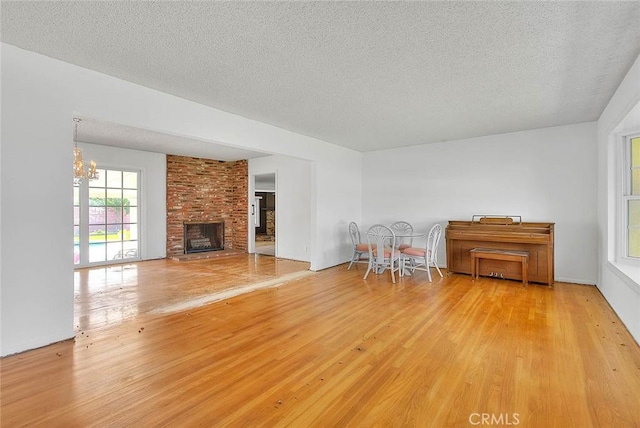 902 W Lucille Ave, West Covina, CA 91790 - living area with wood finished floors, a textured ceiling, a brick fireplace, and a chandelier