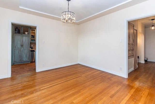 1417 Highland Ave, Needles, CA 92363 - empty room with a chandelier, light wood-style flooring, and a tray ceiling