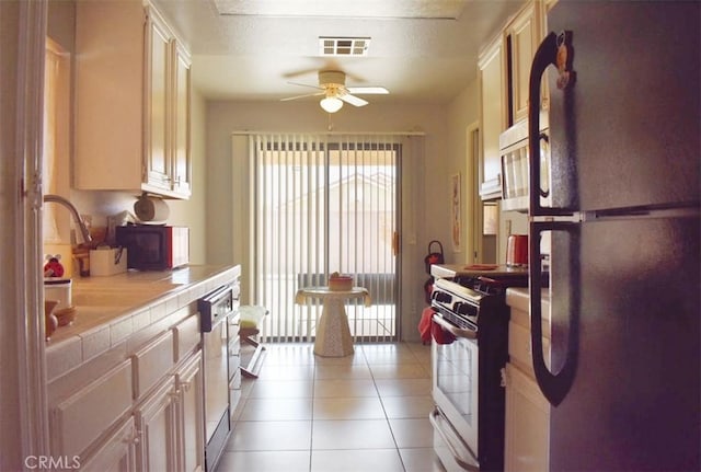 813 Cortez Dr, Hemet, CA 92545 - kitchen featuring freestanding refrigerator, tile countertops, gas range, a ceiling fan, and light tile patterned flooring