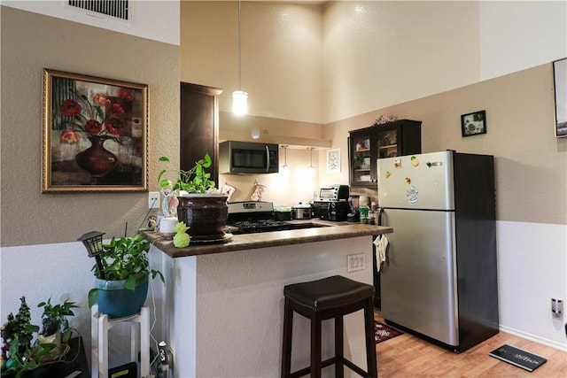 13135 Sunnybrook Cir Unit 205, Garden Grove, CA 92844 - kitchen featuring appliances with stainless steel finishes, light wood finished floors, a towering ceiling, dark countertops, and glass insert cabinets