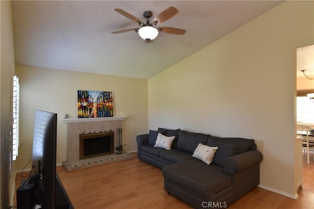 20611 Alaminos Dr, Saugus, CA 91350 - living area featuring vaulted ceiling, ceiling fan, light wood-style flooring, a fireplace with raised hearth, and a textured ceiling