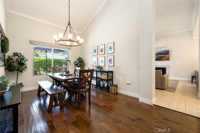 2666 Peacock Pl, La Verne, CA 91750 - dining space with crown molding, a chandelier, high vaulted ceiling, a fireplace, and dark wood-type flooring