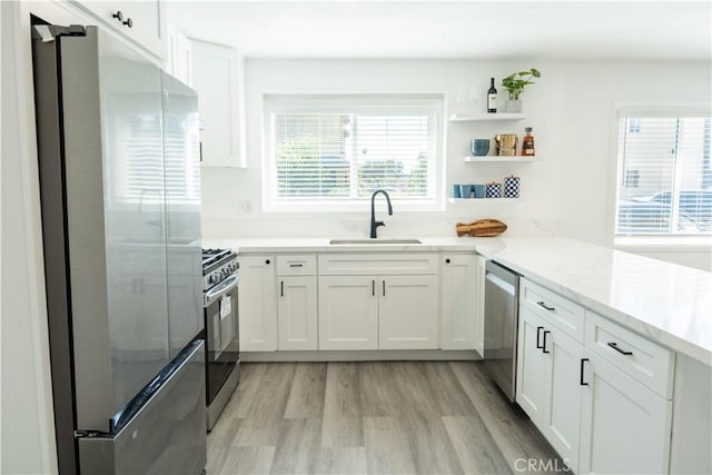 41 Scottsdale S, Carson, CA 90745 - kitchen featuring appliances with stainless steel finishes, white cabinets, light wood finished floors, light stone countertops, and a peninsula