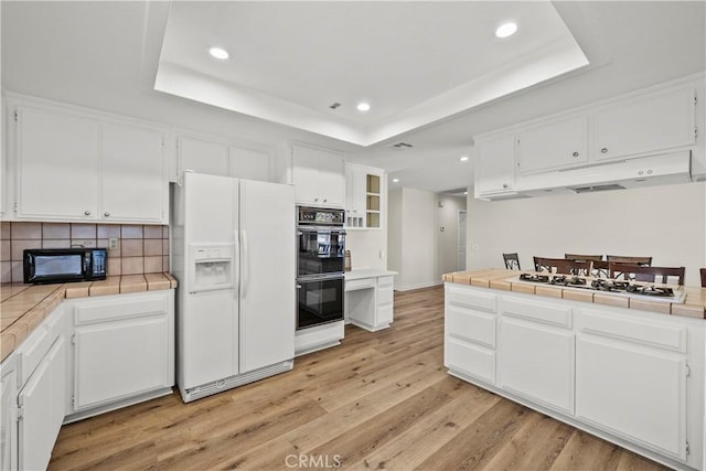 8558 W W Ave E8, Lancaster, CA 93536 - kitchen featuring black appliances, tile counters, a raised ceiling, white cabinetry, and recessed lighting