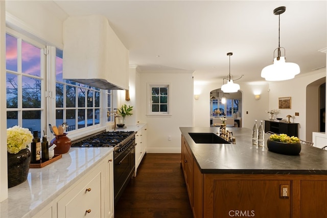 4730 Angeles Vista Blvd, View Park, CA 90043 - kitchen with ventilation hood, range with two ovens, arched walkways, dark wood-style flooring, and brown cabinets