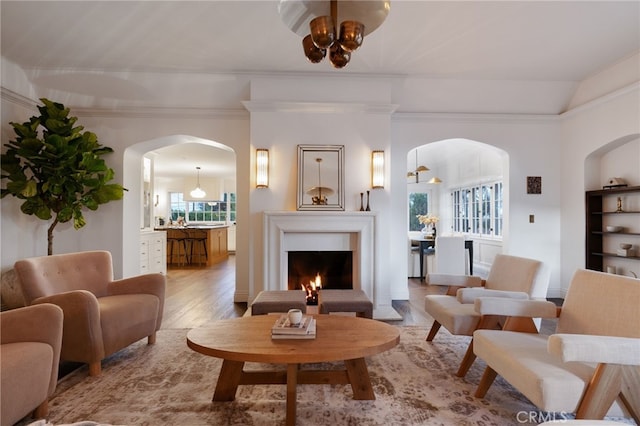 4730 Angeles Vista Blvd, View Park, CA 90043 - living room with arched walkways, wood finished floors, a warm lit fireplace, a chandelier, and crown molding