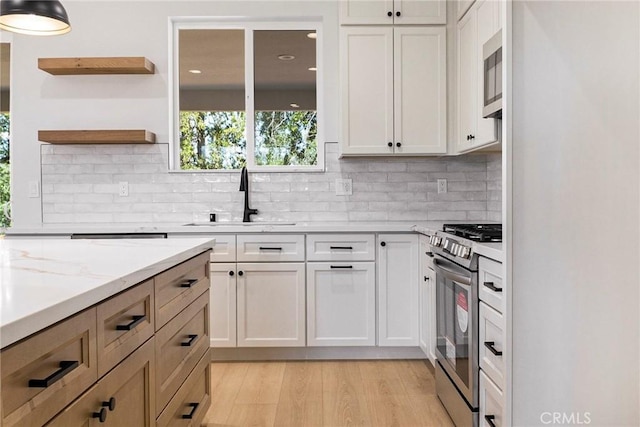5909 Del Mar Ave, Paradise, CA 95969 - kitchen featuring appliances with stainless steel finishes, open shelves, light wood-style floors, tasteful backsplash, and light stone countertops