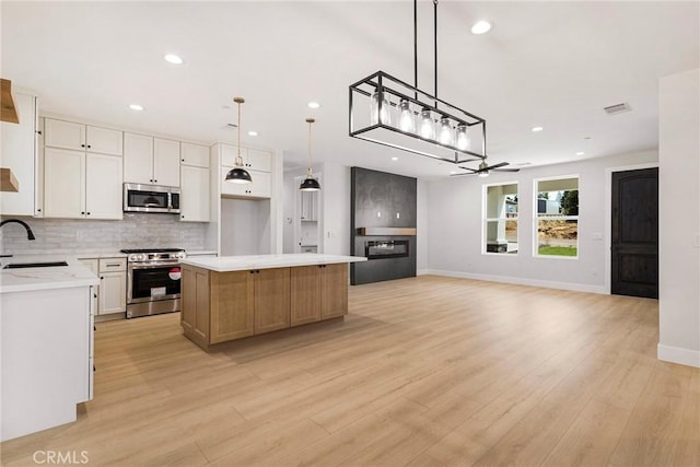5909 Del Mar Ave, Paradise, CA 95969 - kitchen featuring appliances with stainless steel finishes, backsplash, a kitchen island, a ceiling fan, and light wood-style floors