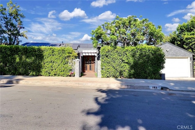 182 Denslow Ave, Los Angeles, CA 90049 - view of property hidden behind natural elements with solar panels, driveway, and an attached garage