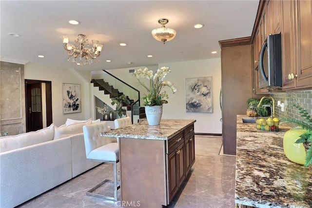 182 Denslow Ave, Los Angeles, CA 90049 - kitchen with stainless steel microwave, recessed lighting, open floor plan, a kitchen bar, and backsplash
