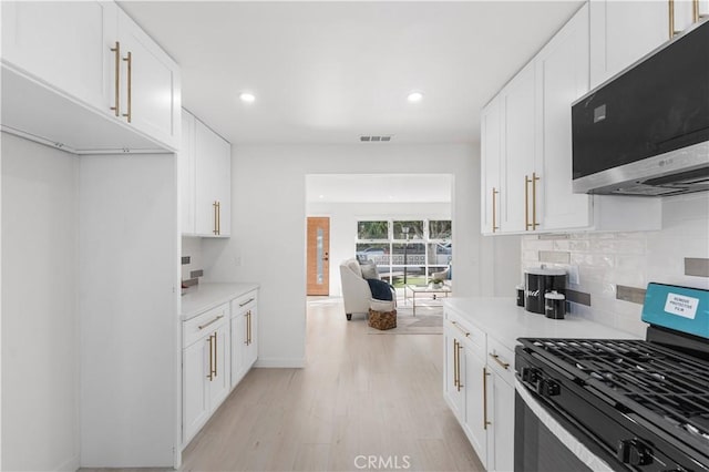 611 Griffith St, San Fernando, CA 91340 - kitchen with gas range oven, stainless steel microwave, light wood-style floors, backsplash, and recessed lighting