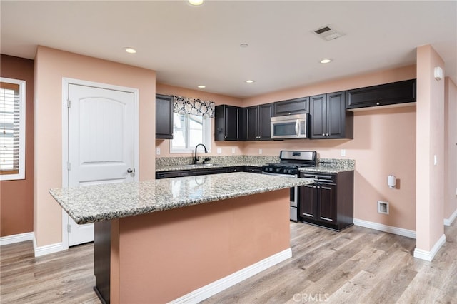 26649 Azalea St, Moreno Valley, CA 92555 - kitchen featuring appliances with stainless steel finishes, a kitchen island, light stone countertops, light wood-style floors, and recessed lighting