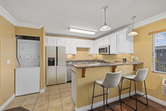 800 N Mollison Ave Unit 56, El Cajon, CA 92021 - kitchen with stacked washer and clothes dryer, appliances with stainless steel finishes, white cabinetry, a peninsula, and a breakfast bar area