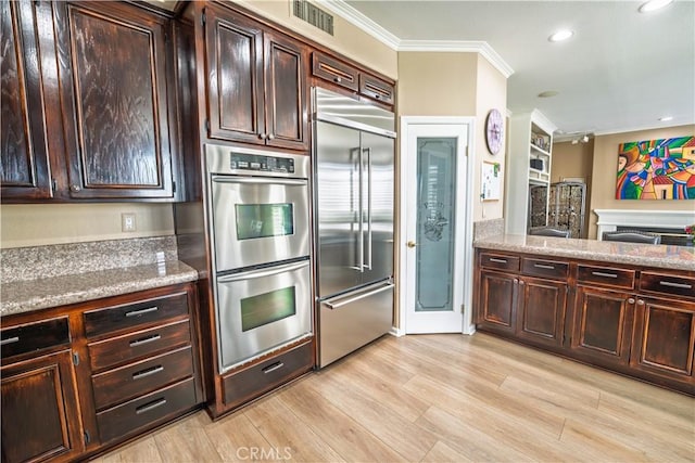 39560 Tinderbox Way, Murrieta, CA 92562 - kitchen with appliances with stainless steel finishes, ornamental molding, light wood-style floors, dark brown cabinets, and recessed lighting