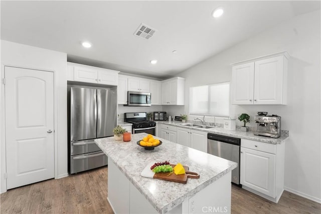 10335 Saint Andrews Ct, Adelanto, CA 92301 - kitchen featuring appliances with stainless steel finishes, lofted ceiling, white cabinets, a center island, and recessed lighting