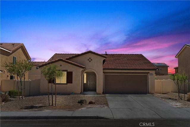 10335 Saint Andrews Ct, Adelanto, CA 92301 - mediterranean / spanish house featuring an attached garage, a tile roof, driveway, and stucco siding