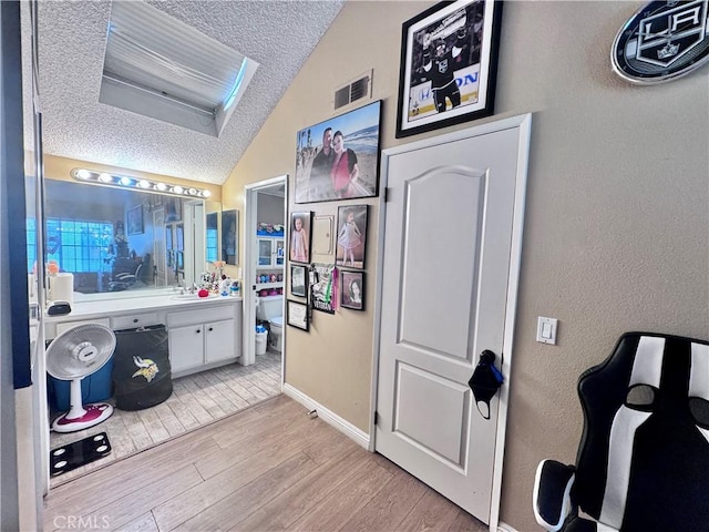 2532 W Macarthur Blvd Unit B, Santa Ana, CA 92704 - bathroom featuring a textured ceiling, lofted ceiling, wood finished floors, vanity, and a textured wall