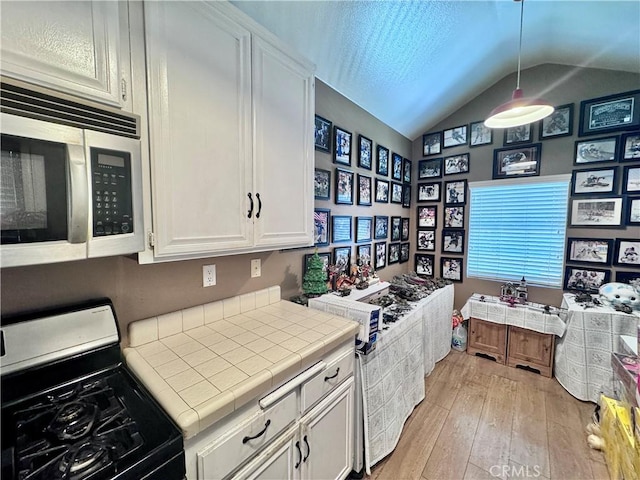 2532 W Macarthur Blvd Unit B, Santa Ana, CA 92704 - kitchen featuring black range with gas cooktop, stainless steel microwave, tile countertops, light wood-style flooring, and white cabinets