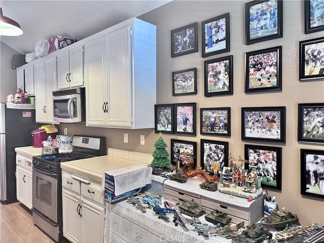 2532 W Macarthur Blvd Unit B, Santa Ana, CA 92704 - kitchen featuring appliances with stainless steel finishes, tile countertops, white cabinets, and light wood finished floors