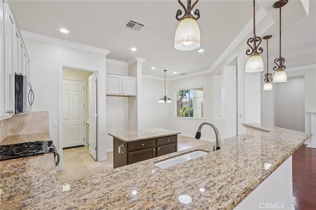 5136 Via Bajamar, Hemet, CA 92545 - kitchen with stainless steel microwave, range with gas cooktop, white cabinetry, crown molding, and a center island