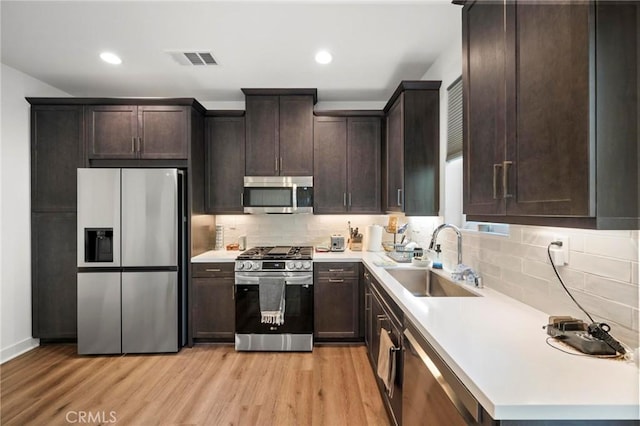 1742 Heywood St Unit C, Simi Valley, CA 93065 - kitchen with stainless steel appliances, dark brown cabinets, light wood finished floors, decorative backsplash, and recessed lighting