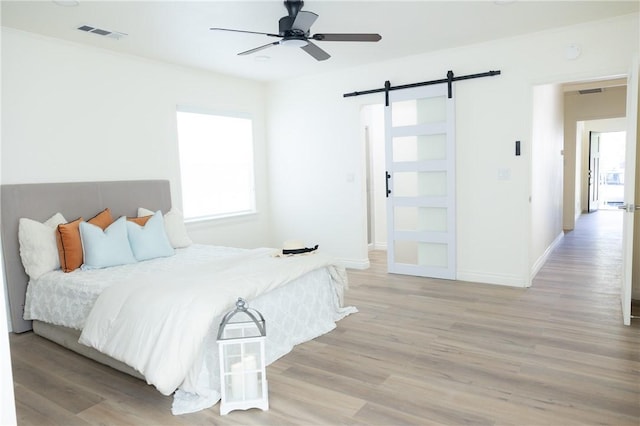 4622 Sunnyside Dr, Riverside, CA 92506 - bedroom with a barn door, light wood-style floors, and a ceiling fan