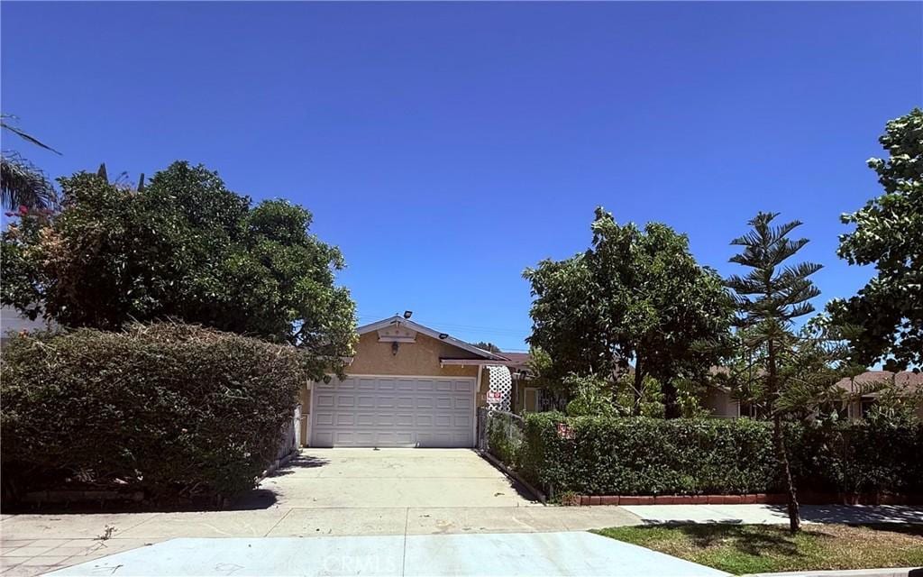 1740 N Del Norte Ave, Ontario, CA 91764 - view of property hidden behind natural elements with driveway, stucco siding, and a garage