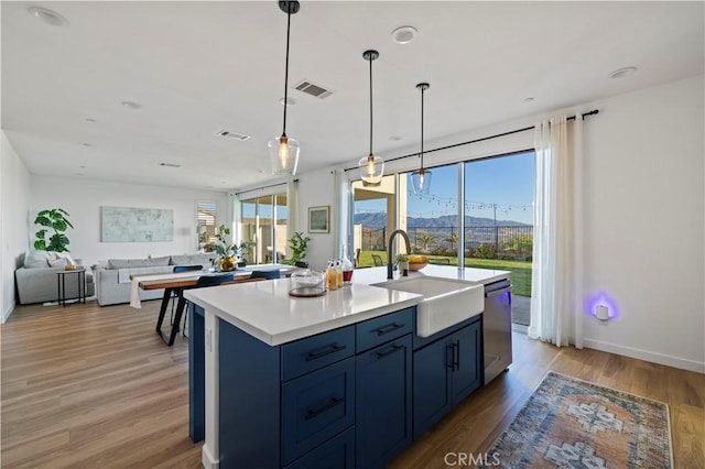 28537 Daybreak Way, Saugus, CA 91350 - kitchen with dishwasher, blue cabinetry, light wood finished floors, open floor plan, and an island with sink