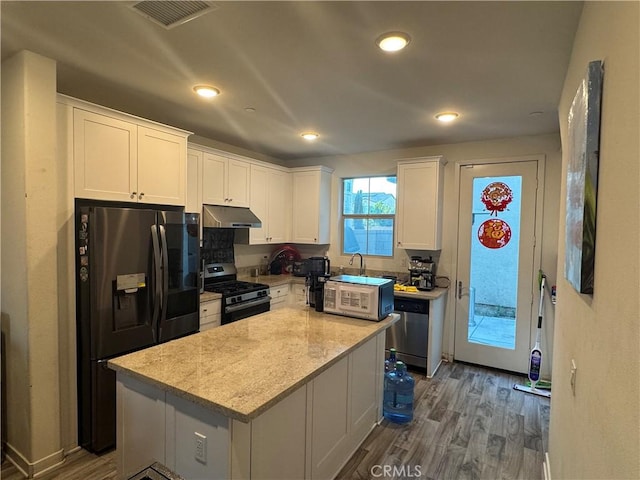 3249 E Butterfly Ln, Ontario, CA 91762 - kitchen with stainless steel appliances, under cabinet range hood, white cabinetry, dark wood-style flooring, and a center island