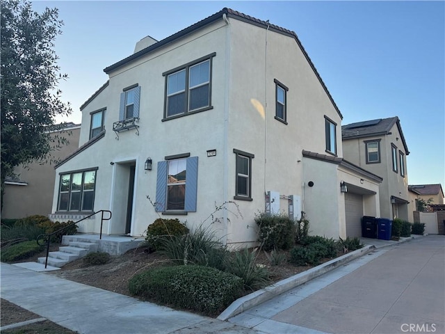 3249 E Butterfly Ln, Ontario, CA 91762 - view of front of home with a garage, stucco siding, driveway, and a chimney