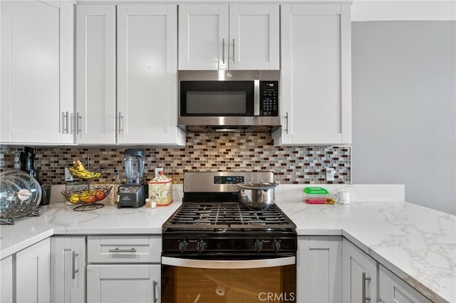 8627 John Ave, Los Angeles, CA 90002 - kitchen with appliances with stainless steel finishes, white cabinets, decorative backsplash, and light stone countertops