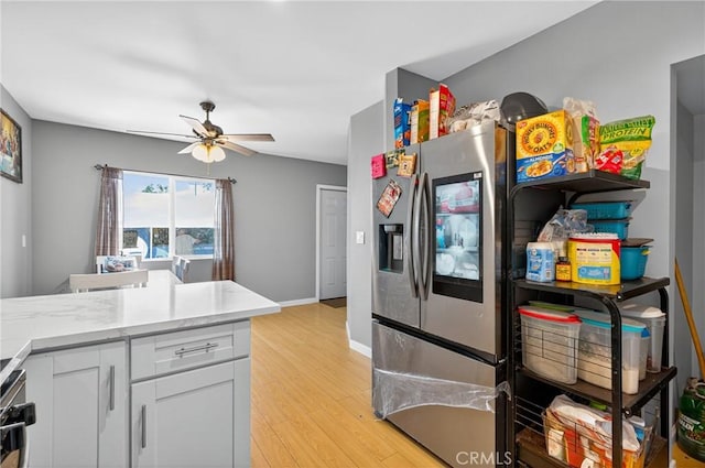 8627 John Ave, Los Angeles, CA 90002 - kitchen with stainless steel refrigerator with ice dispenser, light wood-style floors, a ceiling fan, white cabinetry, and light countertops