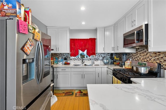 8627 John Ave, Los Angeles, CA 90002 - kitchen with stainless steel appliances, white cabinetry, backsplash, recessed lighting, and light wood-style floors