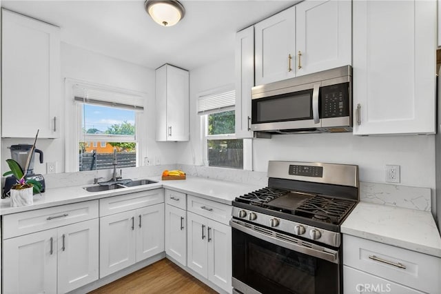 8627 John Ave, Los Angeles, CA 90002 - kitchen featuring stainless steel appliances, healthy amount of natural light, white cabinetry, and light stone countertops
