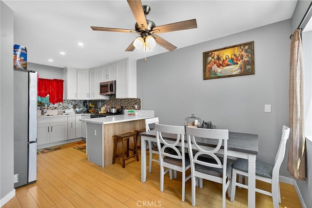 8627 John Ave, Los Angeles, CA 90002 - kitchen with appliances with stainless steel finishes, white cabinetry, tasteful backsplash, ceiling fan, and a peninsula
