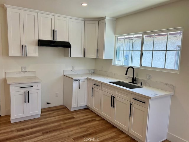 1737 W 65th Pl, Los Angeles, CA 90047 - kitchen with under cabinet range hood, light wood finished floors, white cabinetry, light stone counters, and recessed lighting