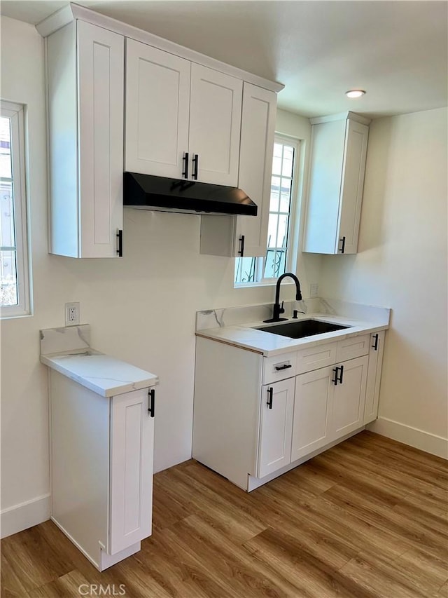 1737 W 65th Pl, Los Angeles, CA 90047 - kitchen featuring under cabinet range hood, light wood-style flooring, light countertops, and white cabinets