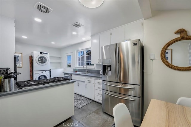 14453 Watkins Dr, La Mirada, CA 90638 - kitchen featuring stainless steel appliances, stacked washer and clothes dryer, dark countertops, white cabinetry, and light tile patterned floors