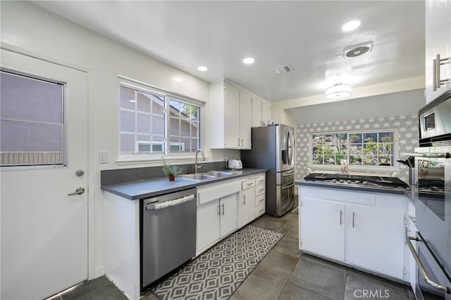 14453 Watkins Dr, La Mirada, CA 90638 - kitchen featuring stainless steel appliances, dark countertops, white cabinets, plenty of natural light, and recessed lighting