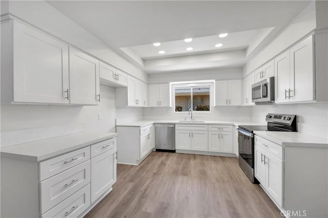 1755 Matthew Ln, Hemet, CA 92545 - kitchen with appliances with stainless steel finishes, a tray ceiling, light wood finished floors, recessed lighting, and white cabinets