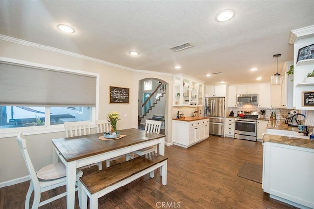 11025 Kenyon Way, Rancho Cucamonga, CA 91701 - dining space with crown molding, arched walkways, dark wood-style floors, recessed lighting, and stairs