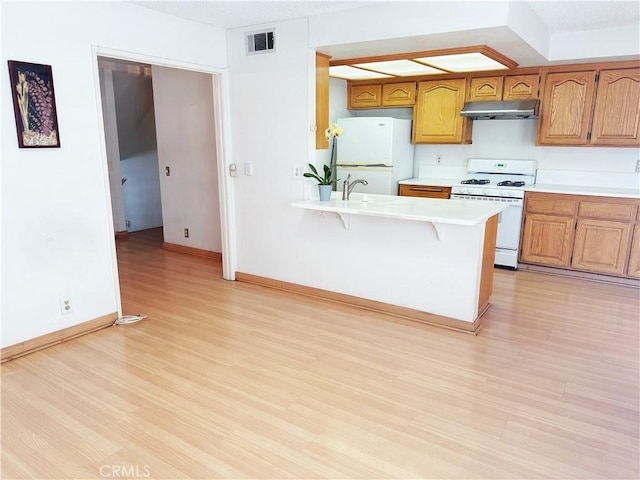 1525 Welldow Ln, Fullerton, CA 92831 - kitchen with white appliances, under cabinet range hood, a peninsula, light wood-style flooring, and light countertops